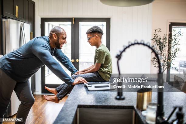 father talking with tween son in residential kitchen - child listening differential focus stock pictures, royalty-free photos & images
