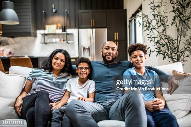 portrait of family on sofa in residential living room - mann bart portrait mit kind stock-fotos und bilder