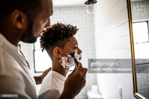 father teaching teenage son to shave in bathroom - no ordinary love stockfoto's en -beelden