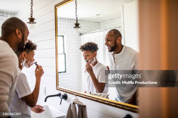 father teaching teenage son to shave in bathroom - barbear imagens e fotografias de stock