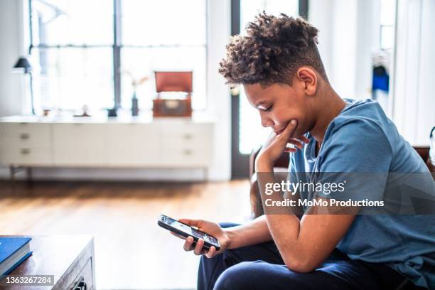 teenage boy using smartphone in residential living room - druck durch gleichaltrige stock-fotos und bilder