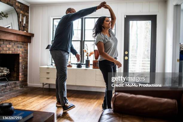 married couple dancing in residential living room - frau tanzt im wohnzimmer stock-fotos und bilder