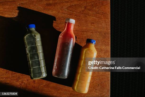 top down image of three bottles of fresh juices in various flavours - softdrinks bottle stock-fotos und bilder