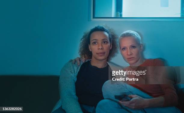 lesbian couple watching tv at night in living room. - woman watching horror movie stock pictures, royalty-free photos & images