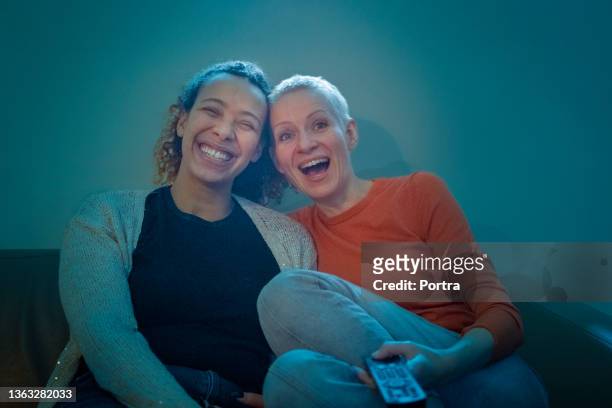 glückliches lesbisches paar, das zu hause eine comedy-show im fernsehen sieht - friends tv show stock-fotos und bilder