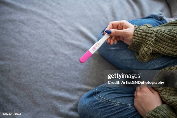 woman holding positive pregnancy test. - infertility stock pictures, royalty-free photos & images