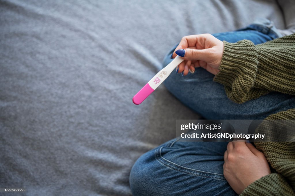 Woman holding positive pregnancy test.