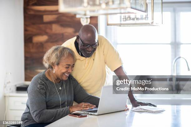 senior couple using laptop in kitchen - relationship stock photos et images de collection