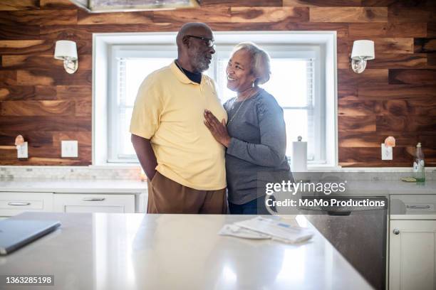 senior couple embracing in kitchen - old rich man stock pictures, royalty-free photos & images