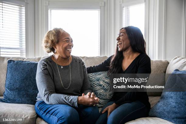 senior mother talking with adult daughter on sofa - vuxet barn bildbanksfoton och bilder