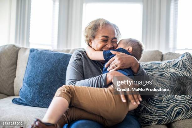 grandmother embracing toddler grandson and laughing - grandmas living room photos et images de collection