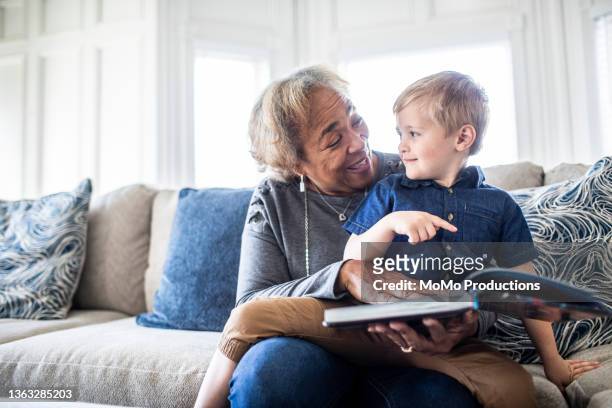 grandmother reading book with toddler grandson - love books stock-fotos und bilder