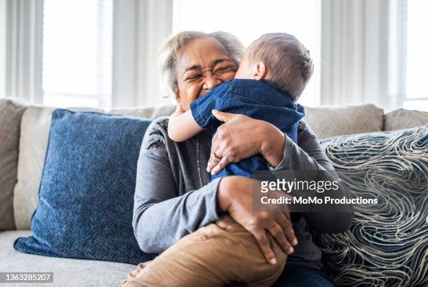 grandmother embracing toddler grandson and laughing - family hugging bright stockfoto's en -beelden