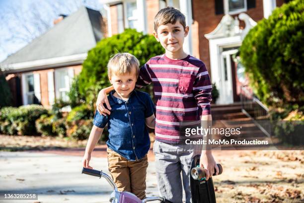 portrait of young boys in front of residential home - brother stock-fotos und bilder