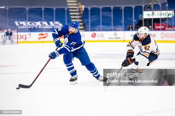 Brodie of the Toronto Maple Leafs plays the puck against Brendan Perlini of the Edmonton Oilers during the first period at the Scotiabank Arena on...