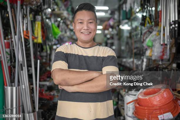 asiatischer chinesischer besitzer lächelt und schaut in die kamera vor hardware-store.as - baumarkt mitarbeiter stock-fotos und bilder