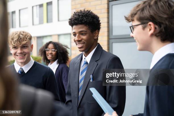 cheerful students in mid-teens interacting between classes - schooluniform stockfoto's en -beelden