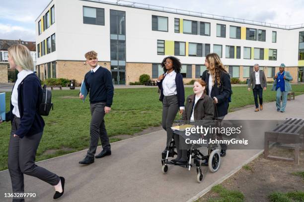 jugendliche klassenkameraden, die über den campus laufen und rollen - rollstuhl schieben stock-fotos und bilder