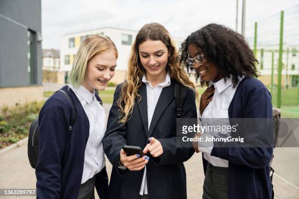 des écolières adolescentes consultent les médias sociaux sur un téléphone intelligent - schoolgirl photos et images de collection