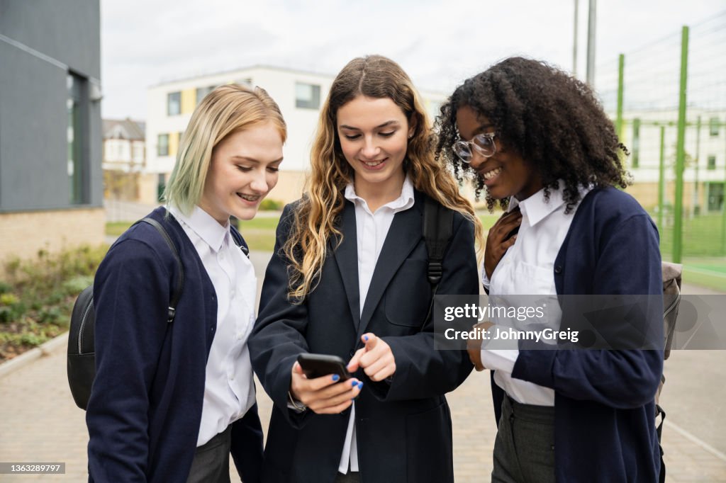Teenage schoolgirls checking social media on smart phone