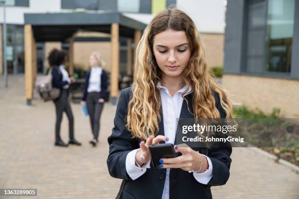 schoolgirl preoccupied with smart phone on secondary campus - secondary school london stock pictures, royalty-free photos & images