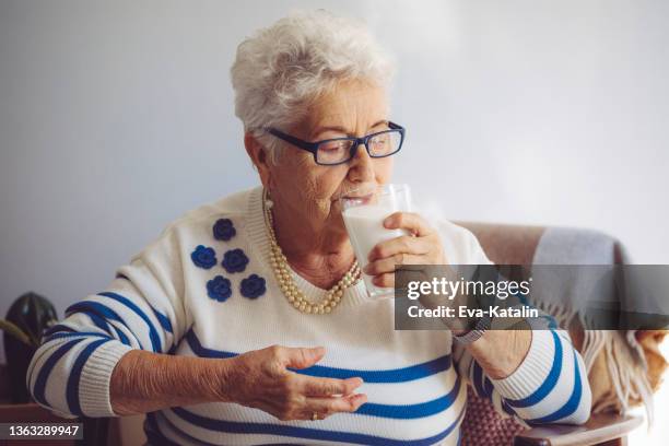 senior woman at home - woman drinking milk stock pictures, royalty-free photos & images