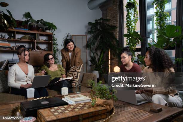 small group of women interact in boho co-working space - coffee table reading mug stock pictures, royalty-free photos & images