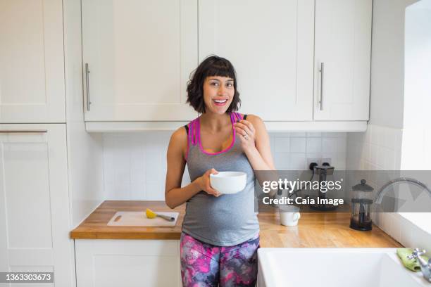 portrait happy pregnant woman eating in kitchen - filipino family eating stock pictures, royalty-free photos & images