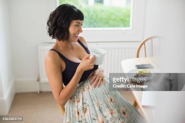 happy pregnant woman drinking tea at laptop - filipino family eating fotografías e imágenes de stock