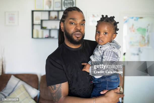 portrait confident father holding toddler son - london not hipster not couple not love not sporty not businessman not businesswoman not young man no stockfoto's en -beelden