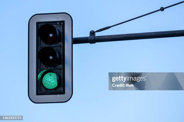 green traffic light with blue sky (germany) - green light stock pictures, royalty-free photos & images