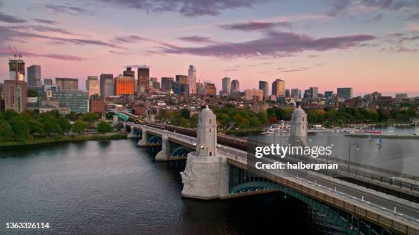 drohnenaufnahme des red line-zuges, der bei sonnenuntergang die longfellow bridge nach boston �überquert - boston beacon hill stock-fotos und bilder