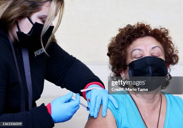 Person receives a COVID-19 vaccination dose, during a free distribution of COVID-19 rapid test kits for those who received vaccination shots or...