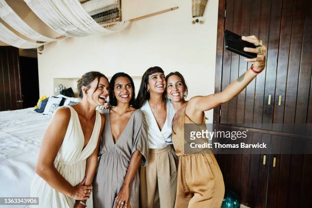 medium wide shot of smiling and laughing bridesmaids taking selfie in luxury hotel suite before wedding - female friendship stock pictures, royalty-free photos & images
