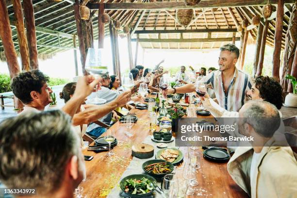 wide shot of guests toasting wine glasses wedding reception dinner at luxury tropical resort - destination wedding imagens e fotografias de stock