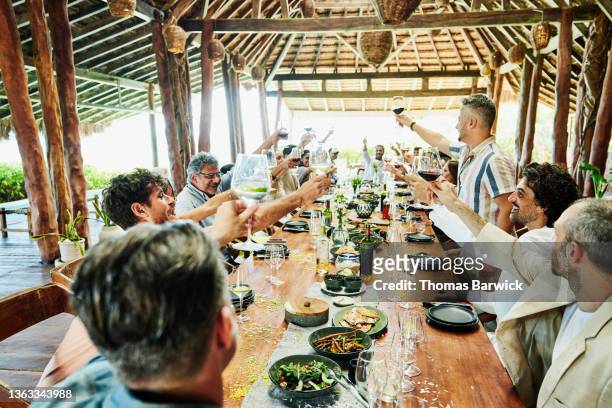 Wide shot of man giving toast during wedding reception dinner at luxury tropical resort