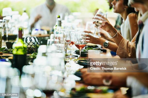 medium wide shot of glass of wine on table during wedding reception at luxury tropical resort - medium group of people foto e immagini stock