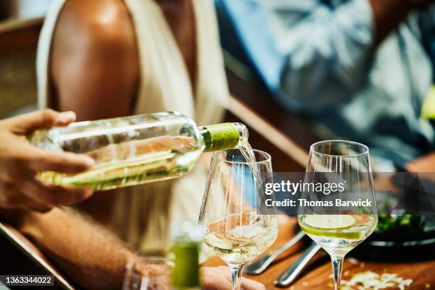 medium close up shot of man pouring wine into glass during wedding reception at tropical resort - spilling stock pictures, royalty-free photos & images