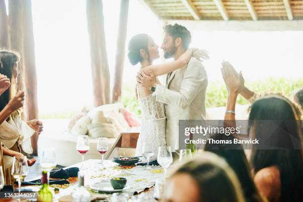 medium wide shot of bride and groom about to kiss during wedding reception dinner at luxury tropical resort - wedding reception stock-fotos und bilder