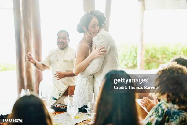 medium wide shot of smiling bride and groom embracing during wedding reception dinner at luxury tropical resort - wedding couple laughing photos et images de collection