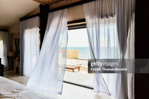 wide shot of curtains blowing in wind in luxury suite at tropical resort - curtain fotografías e imágenes de stock