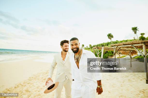 medium wide shot of smiling men hanging out after tropical beach wedding - african ethnicity luxury stock pictures, royalty-free photos & images