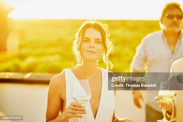 medium shot of woman at sunset rooftop party after wedding at tropical resort - wedding guests stock pictures, royalty-free photos & images