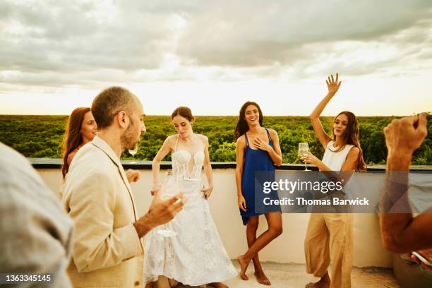 wide shot of bride dancing with friends during sunset rooftop party after wedding at tropical resort - wedding after party fotografías e imágenes de stock