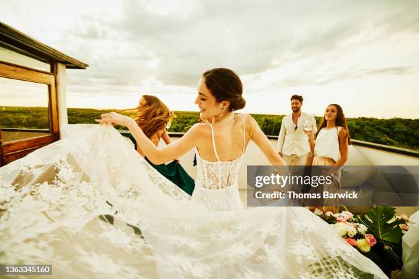 medium wide shot of bride dancing with friends during sunset rooftop party after wedding at tropical resort - hochzeitskleid stock-fotos und bilder