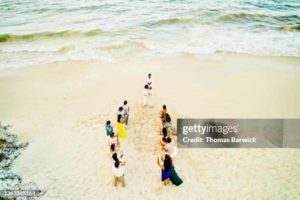 wide shot aerial view of gay couple getting married on tropical beach with friends watching - civil partnership stock pictures, royalty-free photos & images