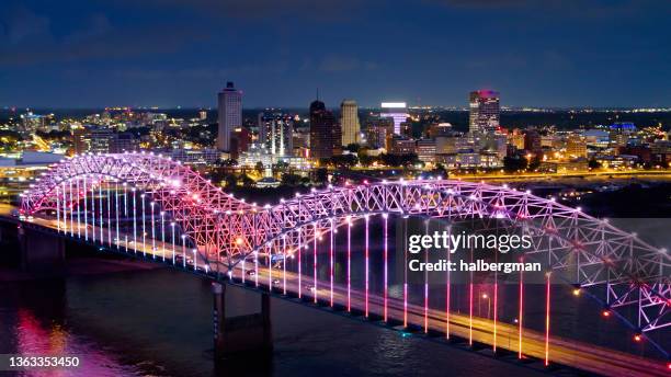 pink and purple lights shimmering on hernando de soto bridge over mississippi river - v memphis stockfoto's en -beelden