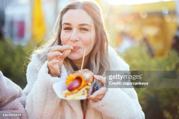 young pretty girl eating big hotdog in fastfood restaurant - hot big women stockfoto's en -beelden
