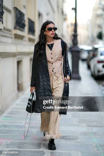 Gabriella Berdugo wears sunglasses, earrings, a black leather padded long winter coat from Copenhagen Muse, a beige jacket with floral print from...