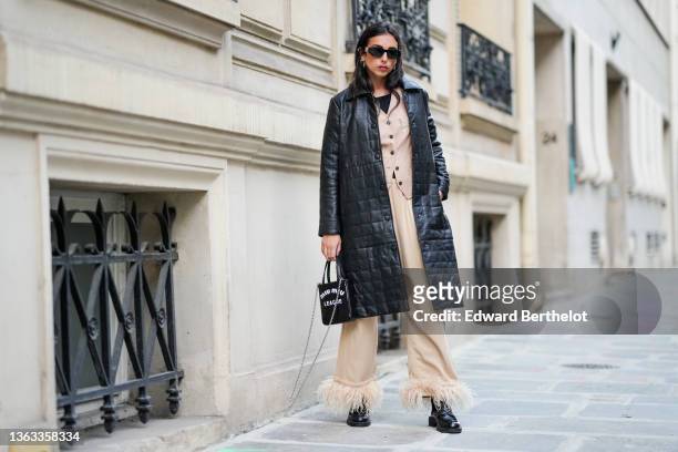 Gabriella Berdugo wears sunglasses, earrings, a black leather padded long winter coat from Copenhagen Muse, a beige jacket with floral print from...